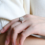 a woman's hand wearing a round brilliant halo lab created diamond ring with pave band alongside a matching eternity ring