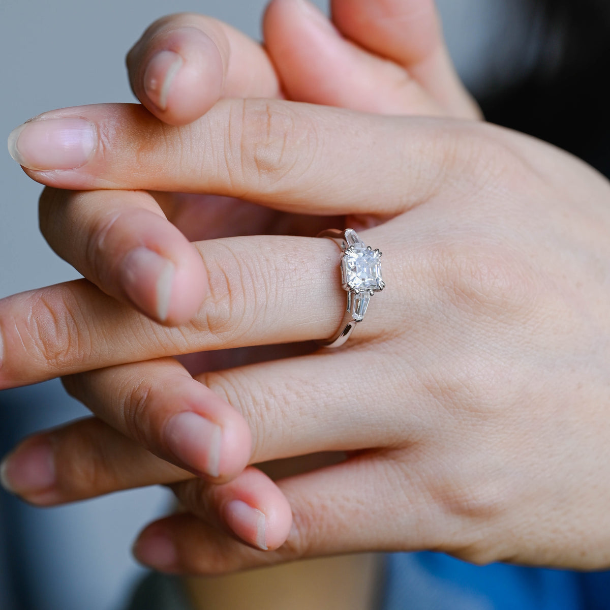 A model wearing a gorgeous three stone asscher cut lab grown diamond ring on her finger.