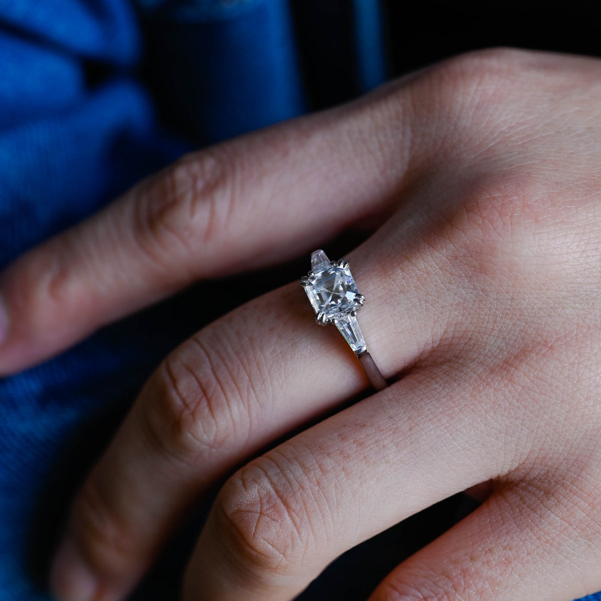 A model wearing a gorgeous three stone asscher cut lab grown diamond ring on her finger.