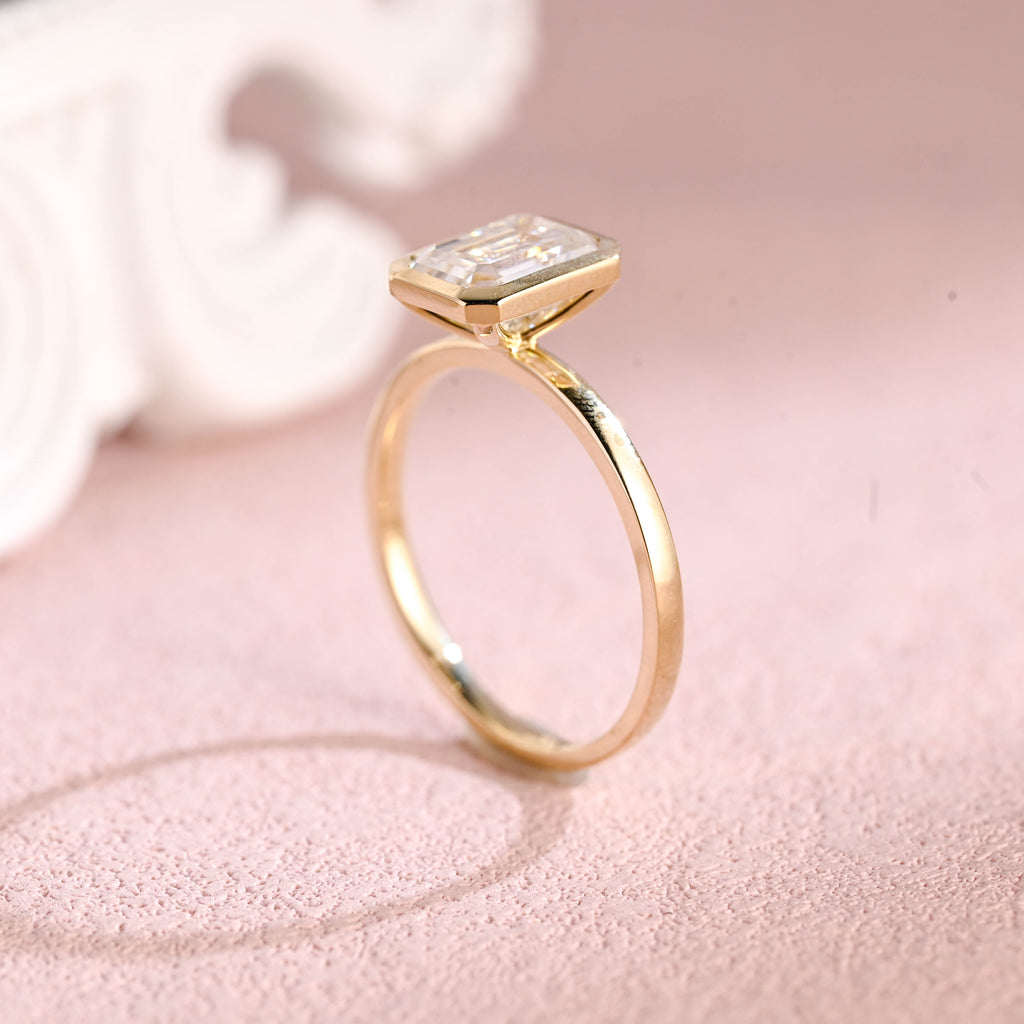 Close up angle shot highlighting the clean step-cut facets of an emerald lab diamond ring.