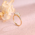A classic 14k yellow gold three stone engagement ring featuring a large emerald cut lab grown diamond flanked by two step-cut side stones.