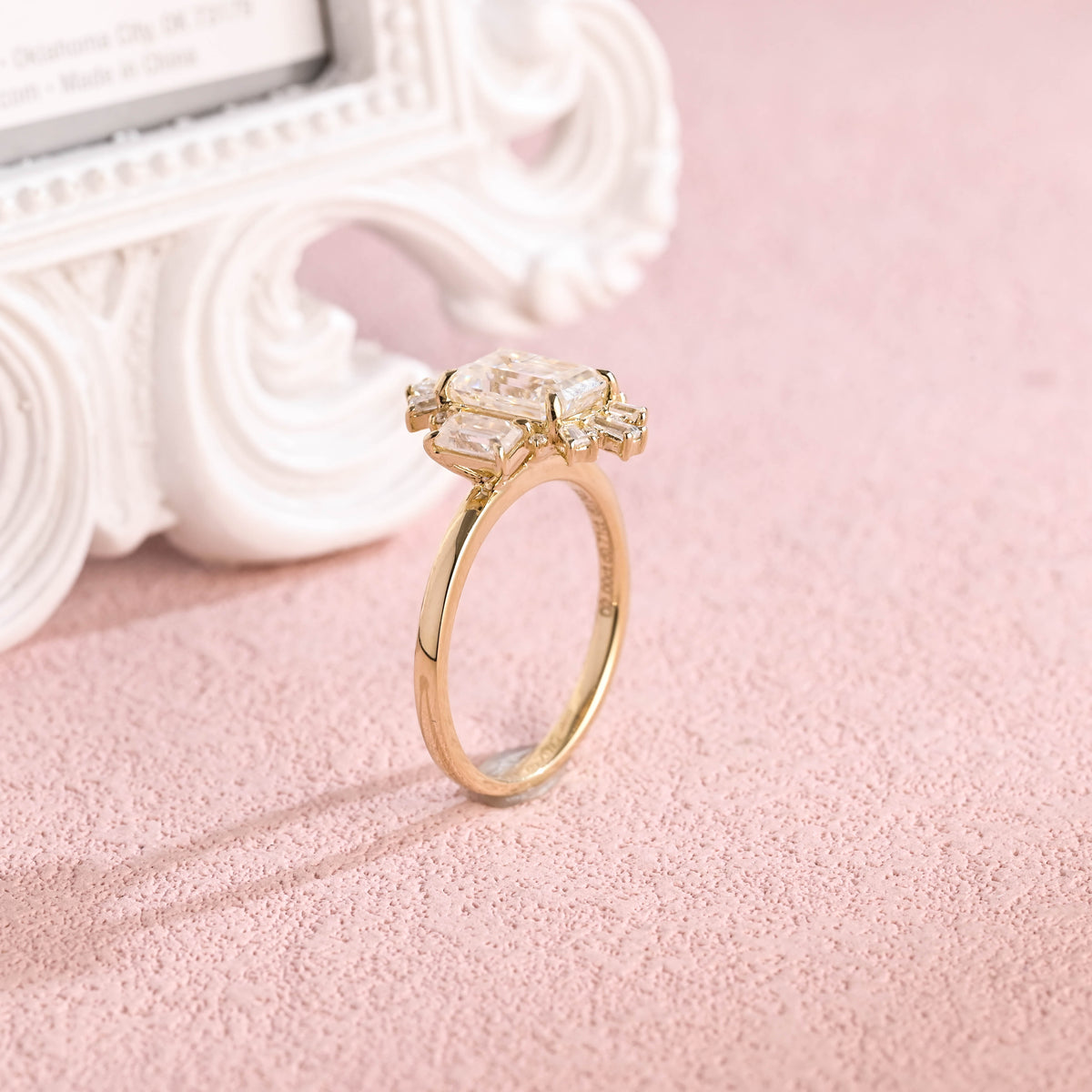 Side profile macro view of an emerald cut lab created diamond halo ring showing secure corner prongs and micro-pave structure.
