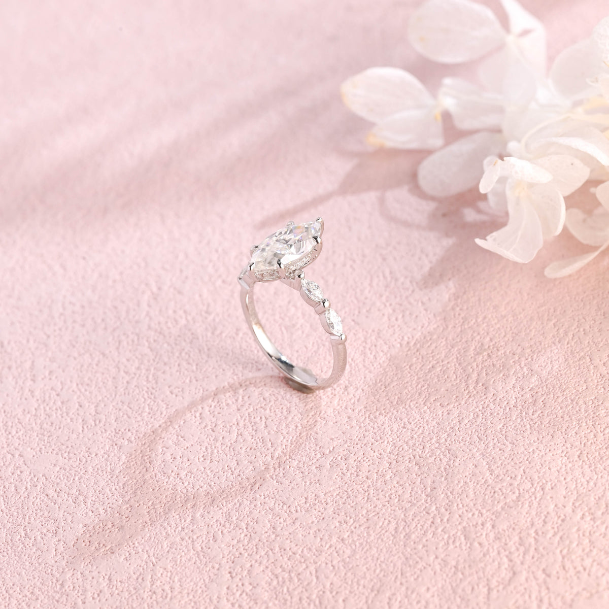 A 14k yellow gold marquise cut lab grown diamond engagement ring with 4 round accent stones on the band and white gold prongs.