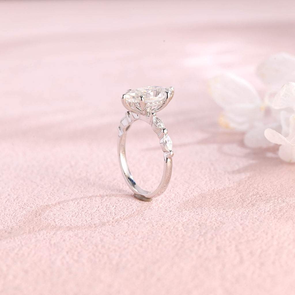 A 14k yellow gold marquise cut lab grown diamond engagement ring with 4 round accent stones on the band and white gold prongs.
