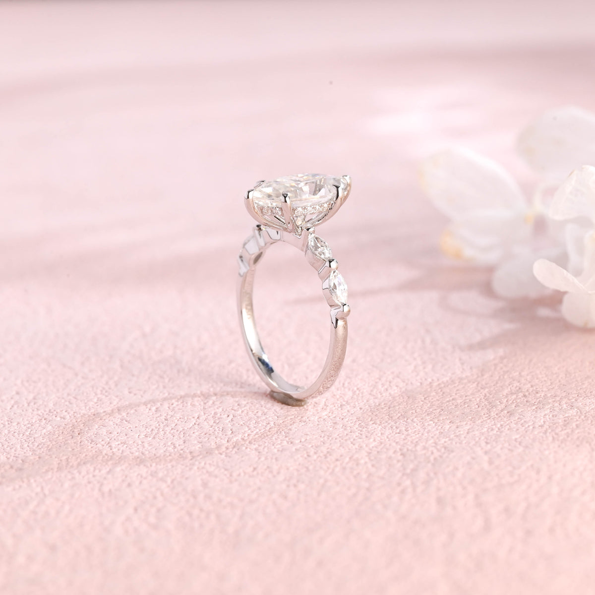 A 14k yellow gold marquise cut lab grown diamond engagement ring with 4 round accent stones on the band and white gold prongs.
