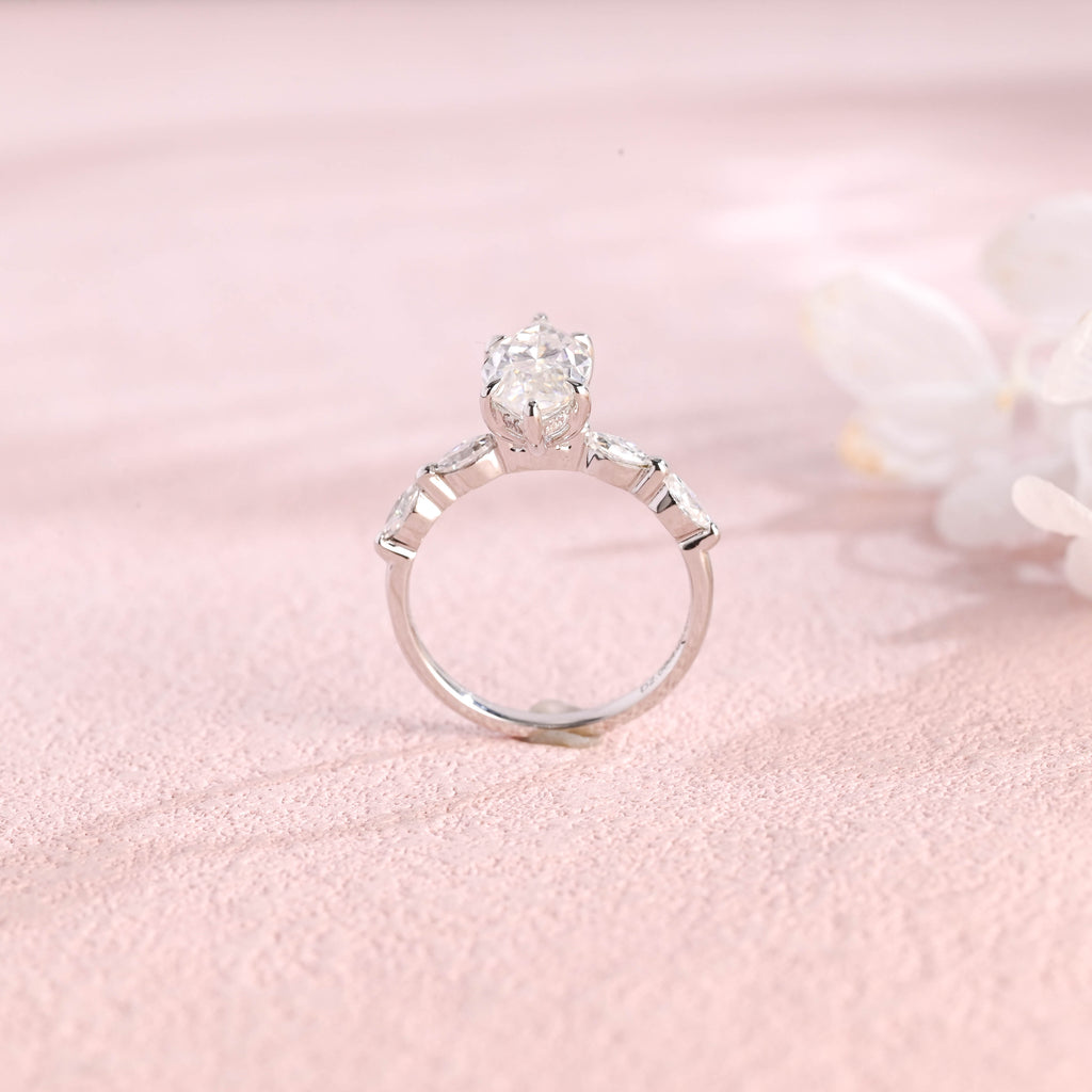 A 14k yellow gold marquise cut lab grown diamond engagement ring with 4 round accent stones on the band and white gold prongs.
