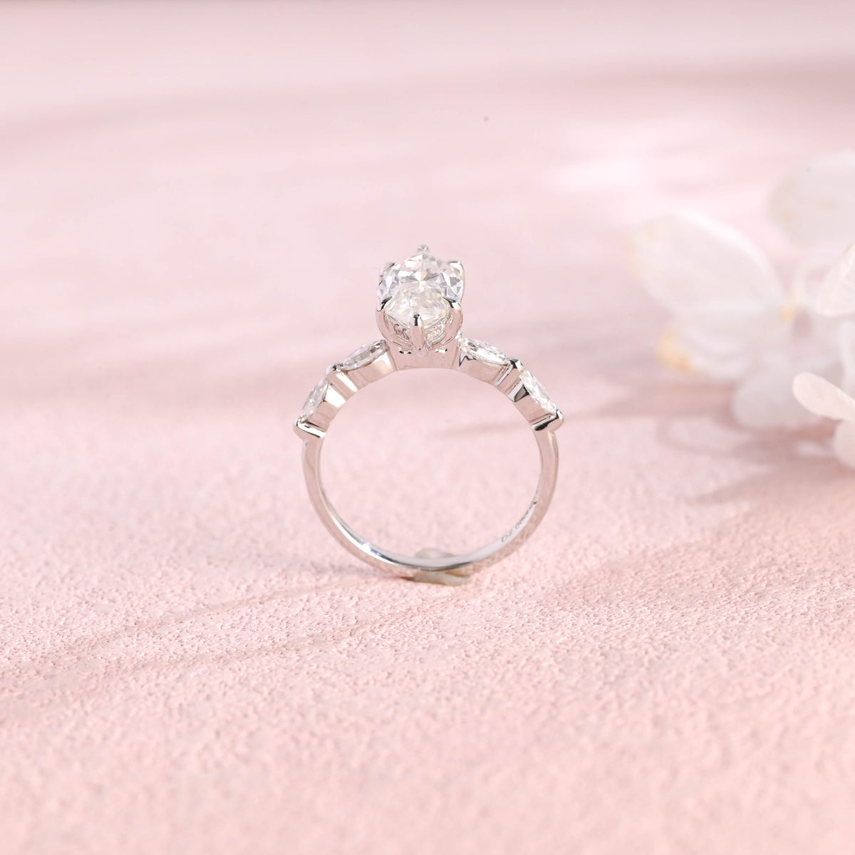 A 14k yellow gold marquise cut lab grown diamond engagement ring with 4 round accent stones on the band and white gold prongs.