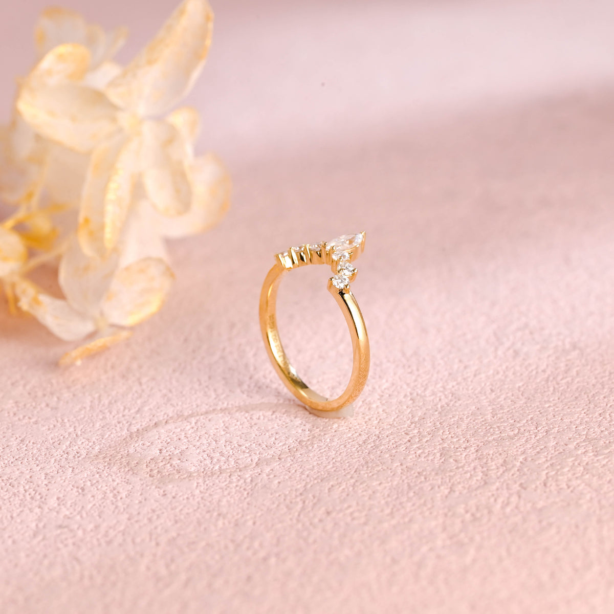 A dainty 14k yellow gold alternating marquise and round lab grown diamond band 0.3 ctw on a neutral background.
