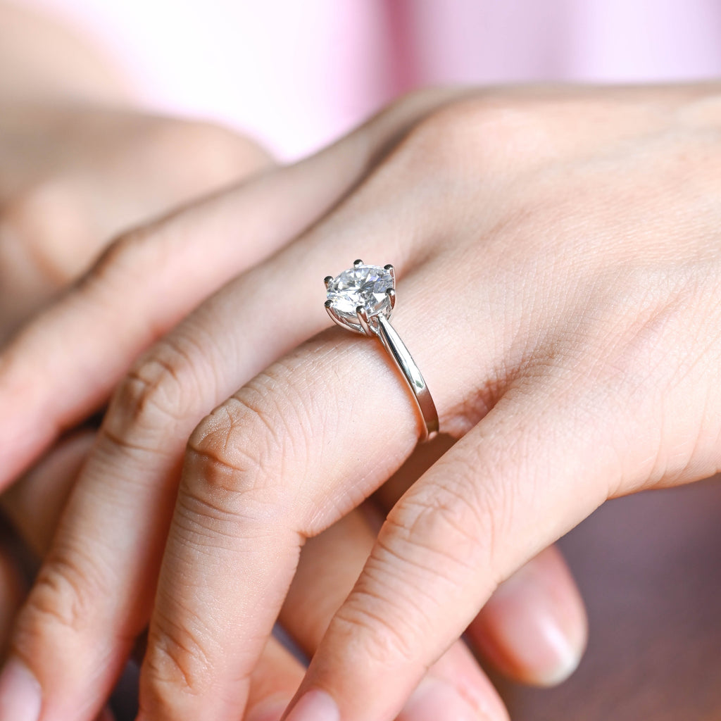 A model wearing a classic six-prong round lab grown diamond engagement ring on her finger.