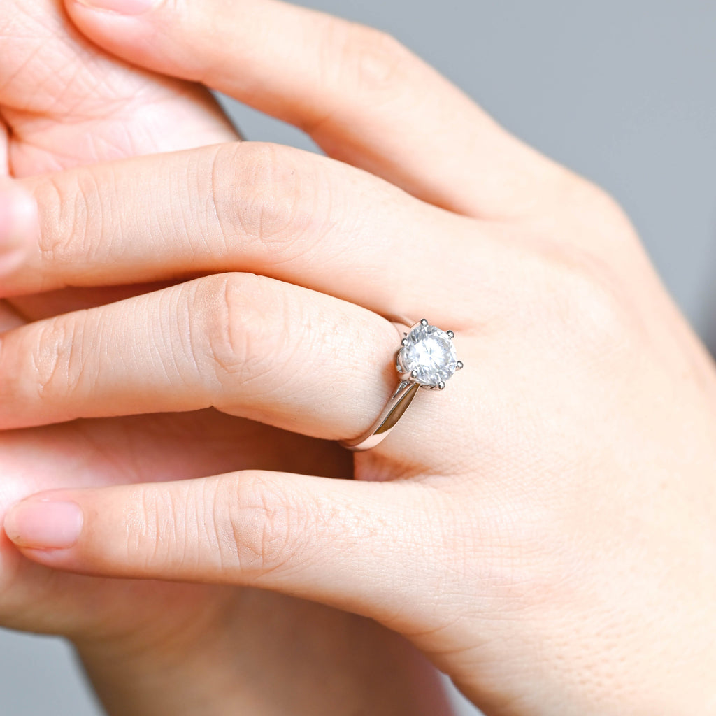 A model wearing a classic six-prong round lab grown diamond engagement ring on her finger.