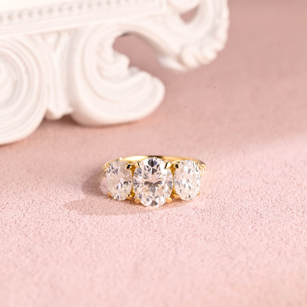 An IGI certified three-stone oval lab grown diamond ring featuring a hidden halo and pave band in gold.